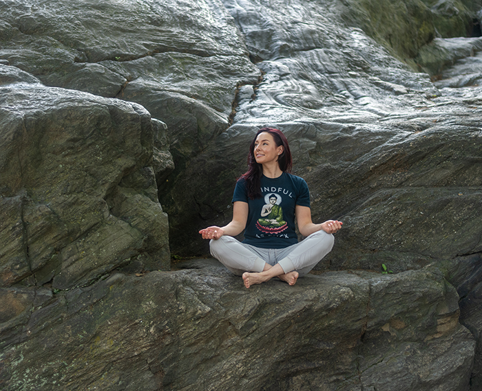 Lina in meditation pose on rocks.